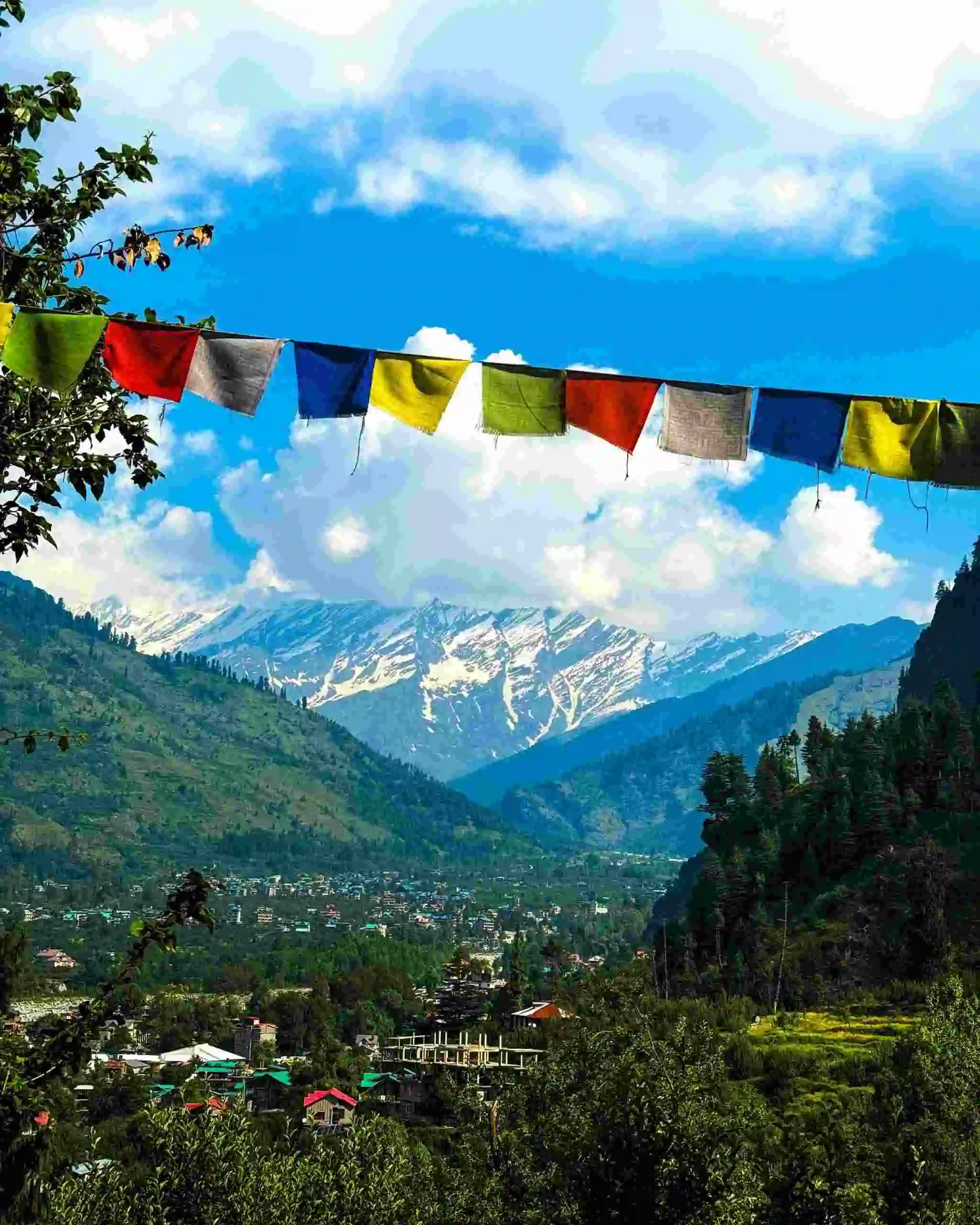 Charming view of Manali village with Himalayan mountains and colorful prayer flags in summer.