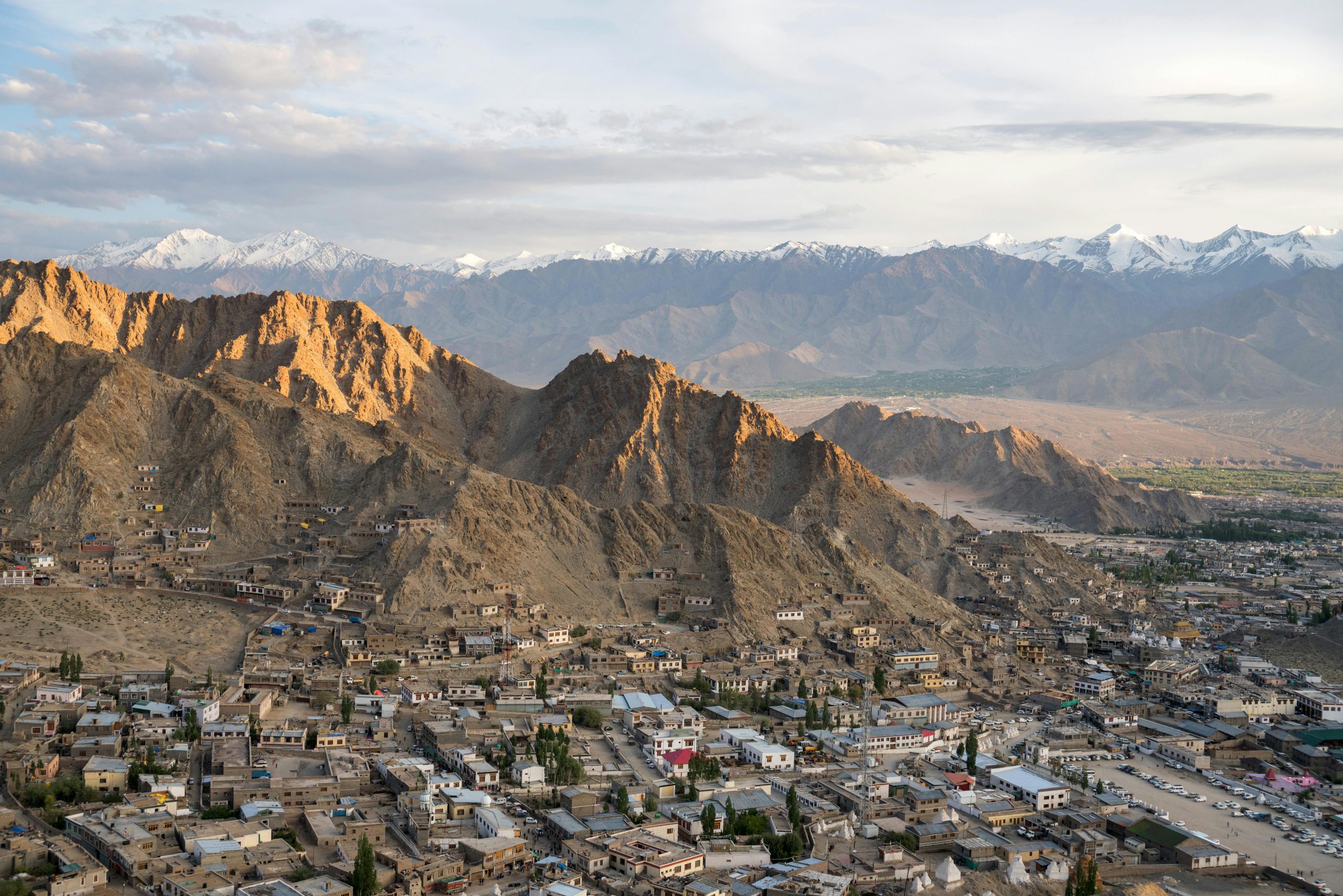A breathtaking aerial view of Leh city surrounded by majestic snowcapped mountains.