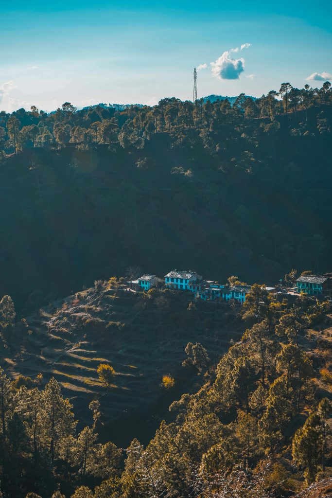 Idyllic village nestled in lush mountains with a sunlit forest view.